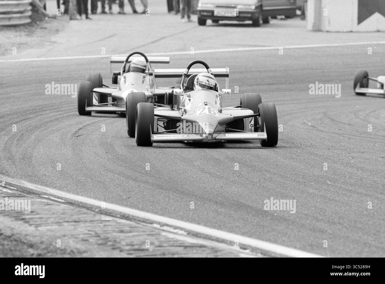 Course automobile Enzo, Lotus series, 19-05-1991 Whizgle News, Dutch Desk, pays-Bas, 1950-2000 deux voitures de course élégantes empruntent une courbe serrée sur un circuit, les moteurs rugissent alors que les pilotes se concentrent farouchement. Les spectateurs et autres véhicules sont visibles en arrière-plan, soulignant l'atmosphère palpitante de la compétition de sport automobile. Banque D'Images