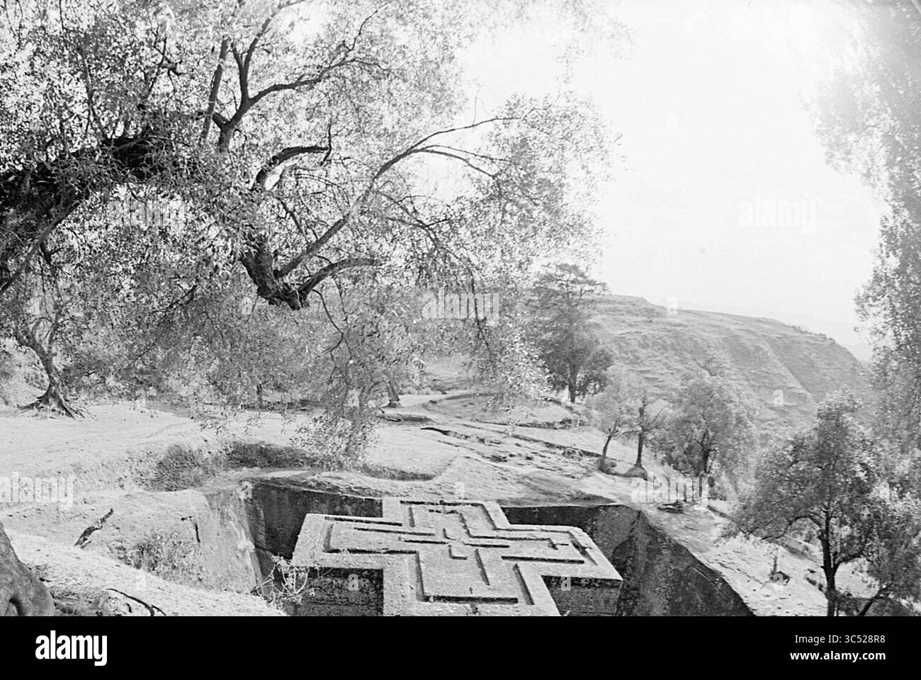Rapport de Poppe de Boer sur l'Ethiopie, Ethiopie, rapport, Ethiopië, 00-02-1971 Whizgle News, Dutch Desk, pays-Bas, 1950-2000 Une grande structure en forme de croix finement sculptée est située dans un paysage rocheux, entouré d'arbres et de terrains vallonnés, évoquant un sens de l'importance historique et culturelle. La lumière du soleil filtre à travers le feuillage, ajoutant une atmosphère sereine à la scène. Banque D'Images
