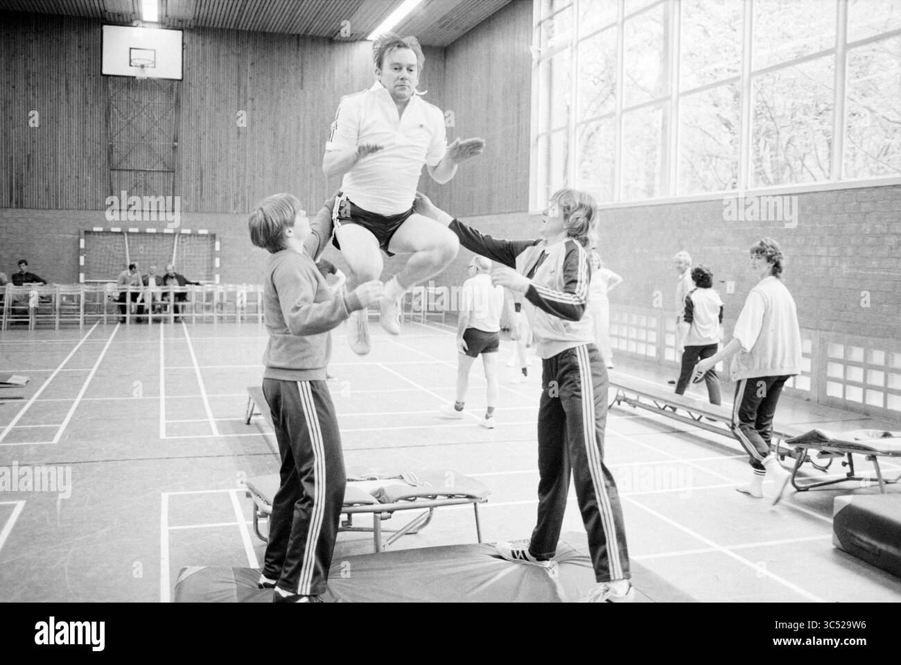 Gymnastique pour les patients cardiaques chez CIO, gymnastique, 11-05-1983 Whizgle News, Dutch Desk, pays-Bas, 1950-2000 un groupe d'athlètes engagés dans un entraînement de gymnastique, avec une personne effectuant un saut tandis que d'autres fournissent soutien et encouragement. L'environnement présente de l'équipement de gymnastique et des spectateurs en arrière-plan, soulignant un sentiment de camaraderie et l'accent mis sur la performance physique. Banque D'Images