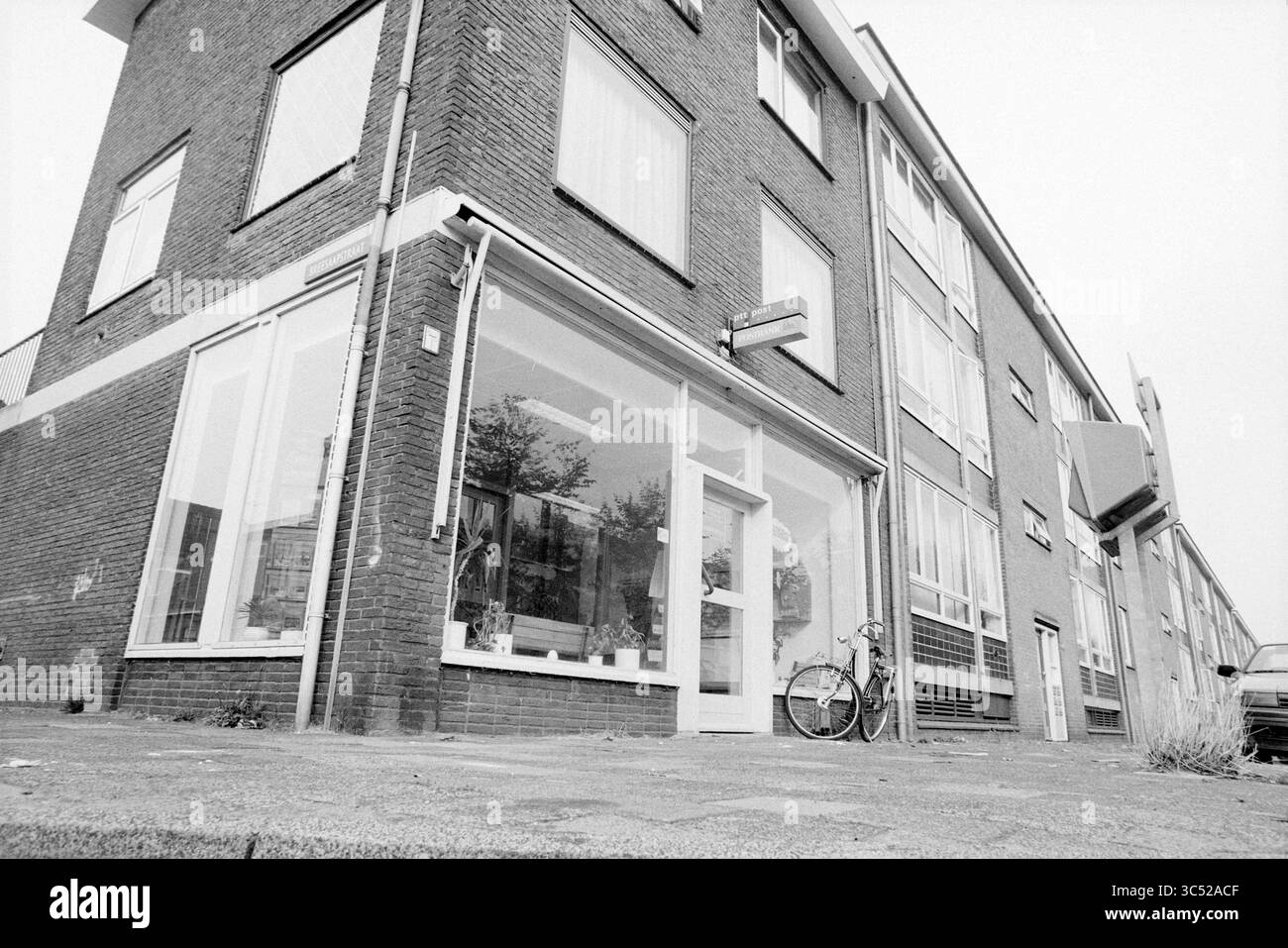Agence de poste Oranjestraat IJmuiden, IJmuiden, Oranjestraat, pays-Bas, 01-10-1990 Whizgle News, Dutch Desk, pays-Bas, 1950-2000 Un bâtiment d'angle dispose de grandes fenêtres affichant une façade, avec un vélo appuyé contre le mur à proximité. La structure présente un mélange d'éléments architecturaux modernes et classiques, entouré d'un trottoir pavé. Banque D'Images