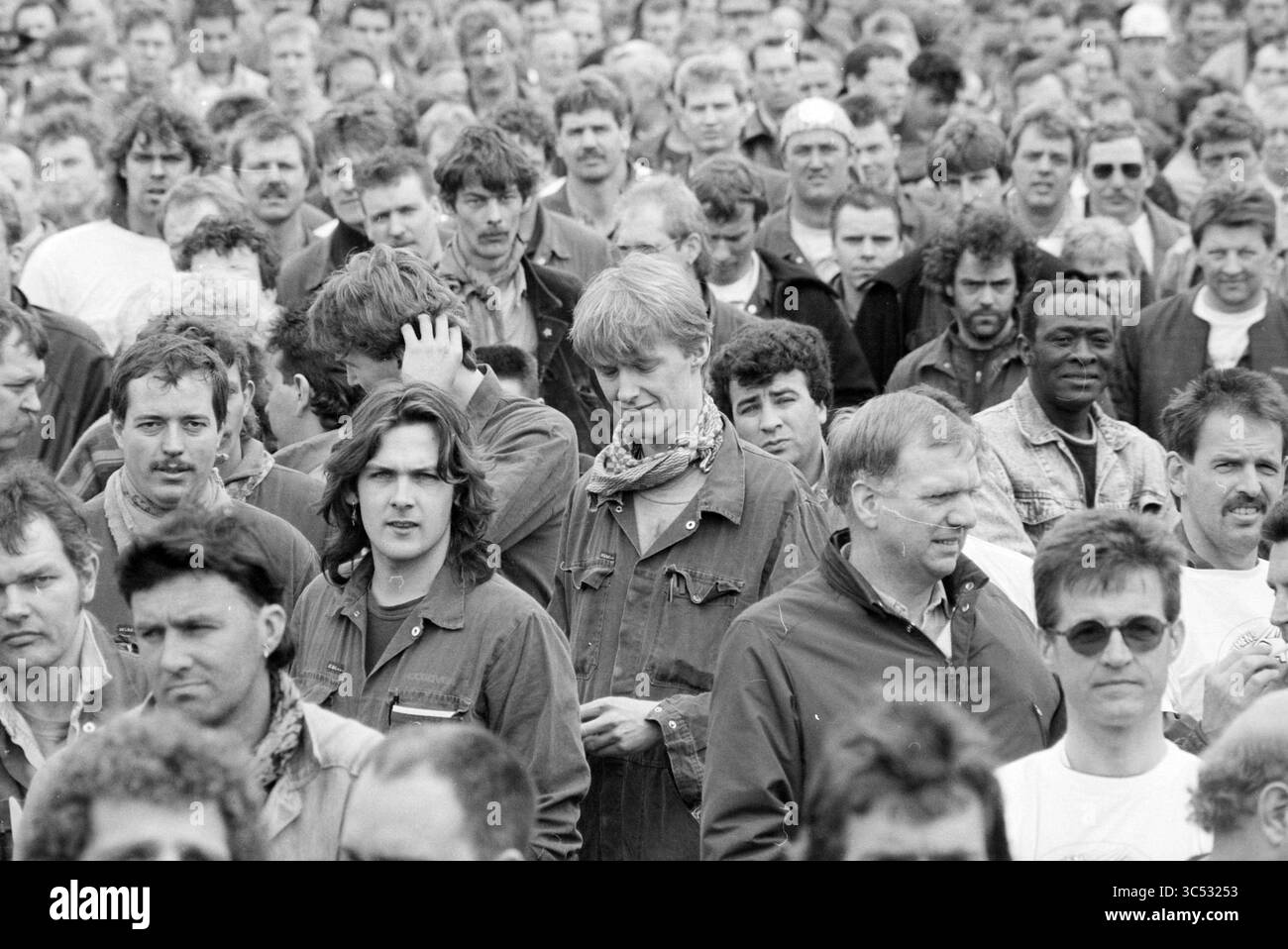 C.A.O. manifestation, Hoogovens, 27-03-1991 Whizgle News, Dutch Desk, pays-Bas, 1950-2000 Une foule dense d'hommes se tient ensemble, affichant un mélange d'expressions allant de la contemplation à la curiosité. Beaucoup sont vêtus de vêtements de travail, avec quelques-uns portant des foulards autour du cou, suggérant un fort sentiment de communauté et de but partagé entre eux. Banque D'Images