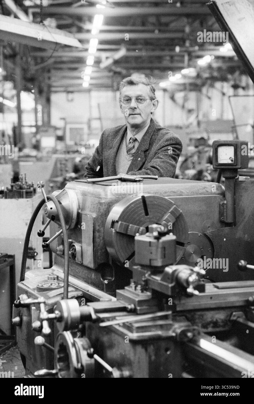 Mr. Sweers, 50 ans de service Conrad Stork, Conrad Stork, 18-11-1986 Whizgle News, Dutch Desk, pays-Bas, 1950-2000 Un machiniste qualifié se tient confiant dans un atelier rempli de divers outils et machines, démontrant son expertise dans l'art du travail des métaux. L'équipement complexe autour de lui met en évidence la complexité de son métier et l'environnement industrieux. Banque D'Images