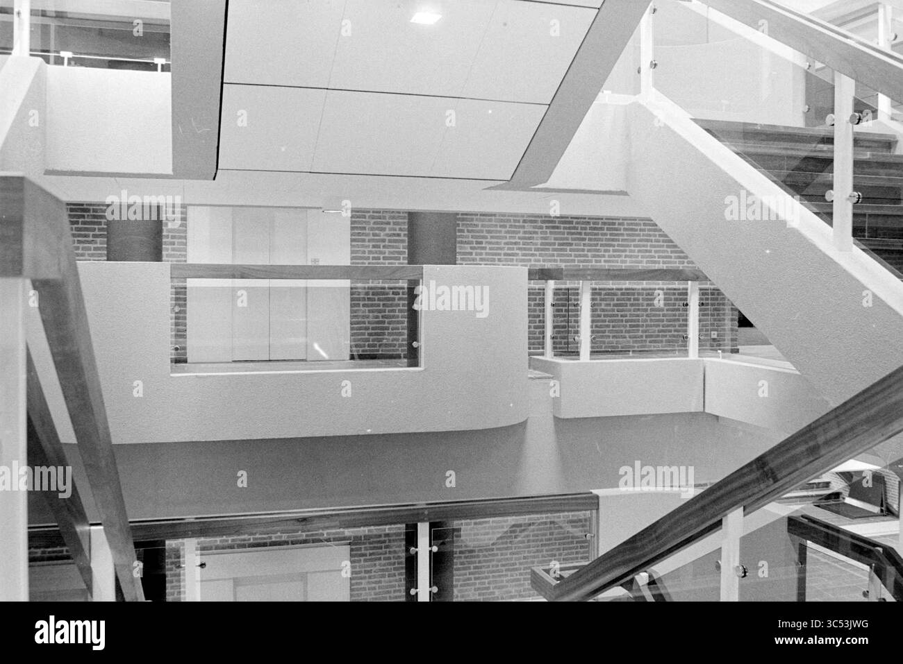 Plan intérieur de la mairie de Hoofddorp, Conseil municipal de Hoofddorp, Hoofddorp, pays-Bas, 06-10-1980 Whizgle News, Dutch Desk, pays-Bas, 1950-2000 Un espace intérieur moderne présentant un escalier élégant à plusieurs niveaux avec des rampes en verre et des lignes géométriques, entouré de murs de briques qui rehaussent le design contemporain. Banque D'Images