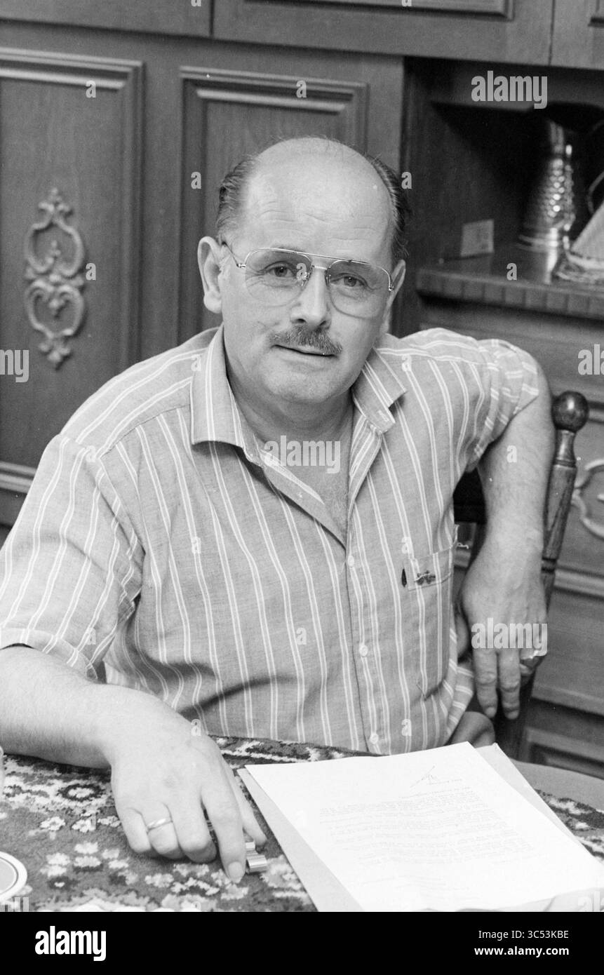 Portrait A. Korringa, Hoofddorp, Portraits, Hoofddorp, pays-Bas, 04-07-1984 Whizgle News, Dutch Desk, pays-Bas, 1950-2000 Un homme d'âge moyen est assis à une table, portant des lunettes et une chemise rayée. Il regarde directement le spectateur avec une expression réfléchie, une main reposant sur un document devant lui. L'arrière-plan présente des armoires en bois, suggérant un cadre intérieur confortable. Banque D'Images