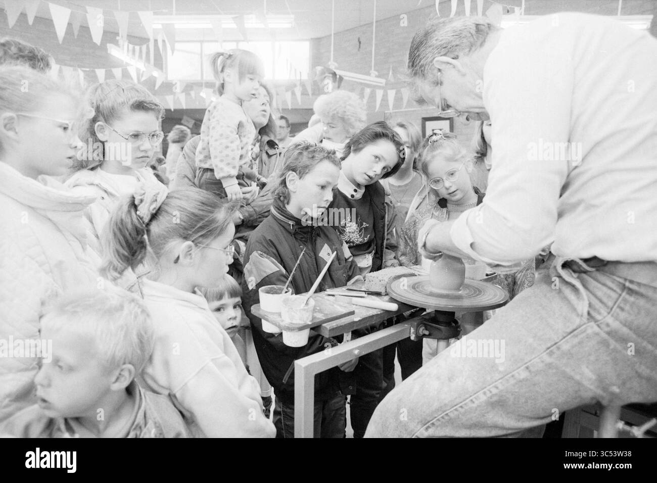 Journée artisanale, école P. Vermeulen, IJm., IJmuiden, pays-Bas, 19-04-1991 Whizgle News, Dutch Desk, pays-Bas, 1950-2000 Un groupe d'enfants captivés regarde attentivement alors qu'un adulte fait une démonstration de poterie lors d'un événement communautaire, entouré d'une guirlande colorée. Banque D'Images Journée artisanale, école P. Vermeulen, IJm., IJmuiden, pays-Bas, 19-04-1991 Whizgle News, Dutch Desk, pays-Bas, 1950-2000 Un groupe d'enfants captivés regarde attentivement alors qu'un adulte fait une démonstration de poterie lors d'un événement communautaire, entouré d'une guirlande colorée. Banque D'Images