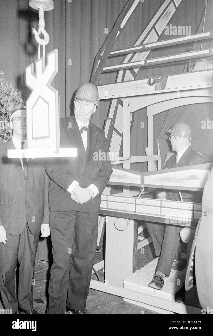 Ouverture du tournoi d'échecs Hoogovens 1966 au Kennemertheater, Beverwijk. Avec Jan Hein donner, Beverwijk, pays-Bas, 00-00-1966 Whizgle News, Dutch Desk, pays-Bas, 1950-2000 Un groupe d'hommes habillés et portant un casque de sécurité observe un grand objet suspendu soulevé par une grue dans un cadre construit. Un homme se tient attentif à côté d'une console tandis qu'un autre regarde depuis un siège voisin, mettant l'accent sur un mélange de célébration et d'industrie lors d'un événement important. Banque D'Images