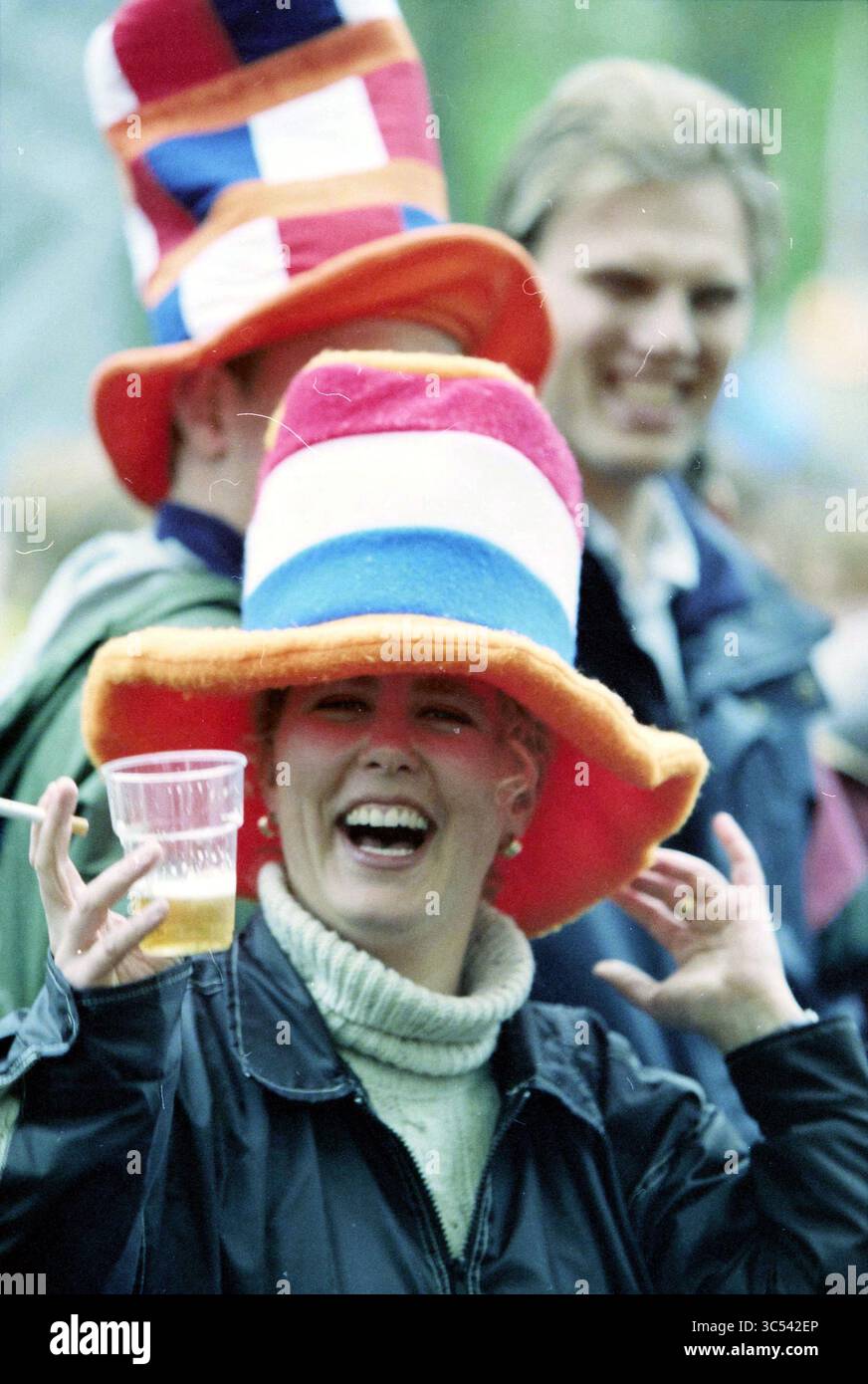 Poupée libération Gil Scott-Heron Haarlem, Haarlem, pays-Bas, 04-05-1998 Whizgle News, Dutch Desk, pays-Bas, 1950-2000 Une femme joyeuse portant un grand chapeau coloré lève une tasse en plastique, souriant largement alors qu'elle aime un rassemblement festif. En arrière-plan, d'autres se joignent à la célébration, ajoutant à l'atmosphère animée. Banque D'Images