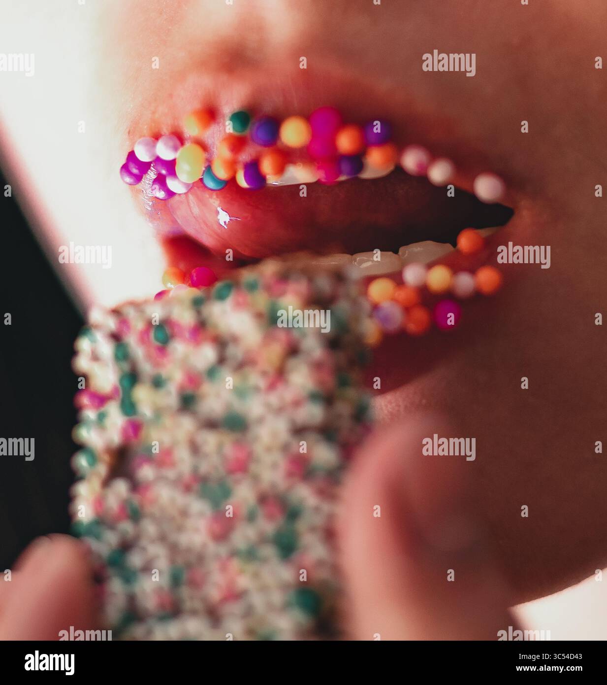 Jeune femme aux lèvres roses mordant des bonbons colorés. ECLAIRAGE naturel, photographie rapprochée. Banque D'Images