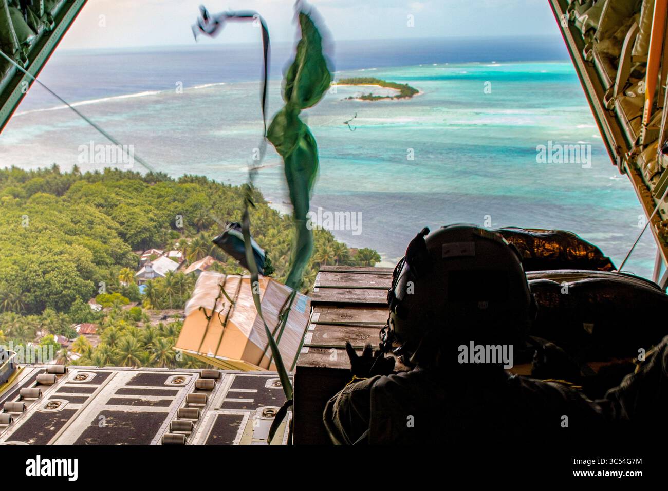 13 décembre 2019 - Andersen Air Force base, Guam - Sgt. D'état-major Sarah Meadows, maître de chargement du 36e escadron de transport aérien de la base aérienne de Yokota, Japon, attend que les deux paquets d'aide humanitaire à faible coût et basse altitude se soient dégagés avant d'exécuter sa propre partie du largage d'avion pendant l'opération Christmas Drop 2019, Nomwin, États fédérés de Micronésie, Dec. 13, 2019. Chaque année, l’OCD sert de terrain d’essai pour les techniques utilisées et partagées entre l’US Air Force et ses partenaires régionaux en préparation pour répondre aux catastrophes naturelles, augmentant ainsi la stabilité et la sécurité régionales. (CRE Banque D'Images