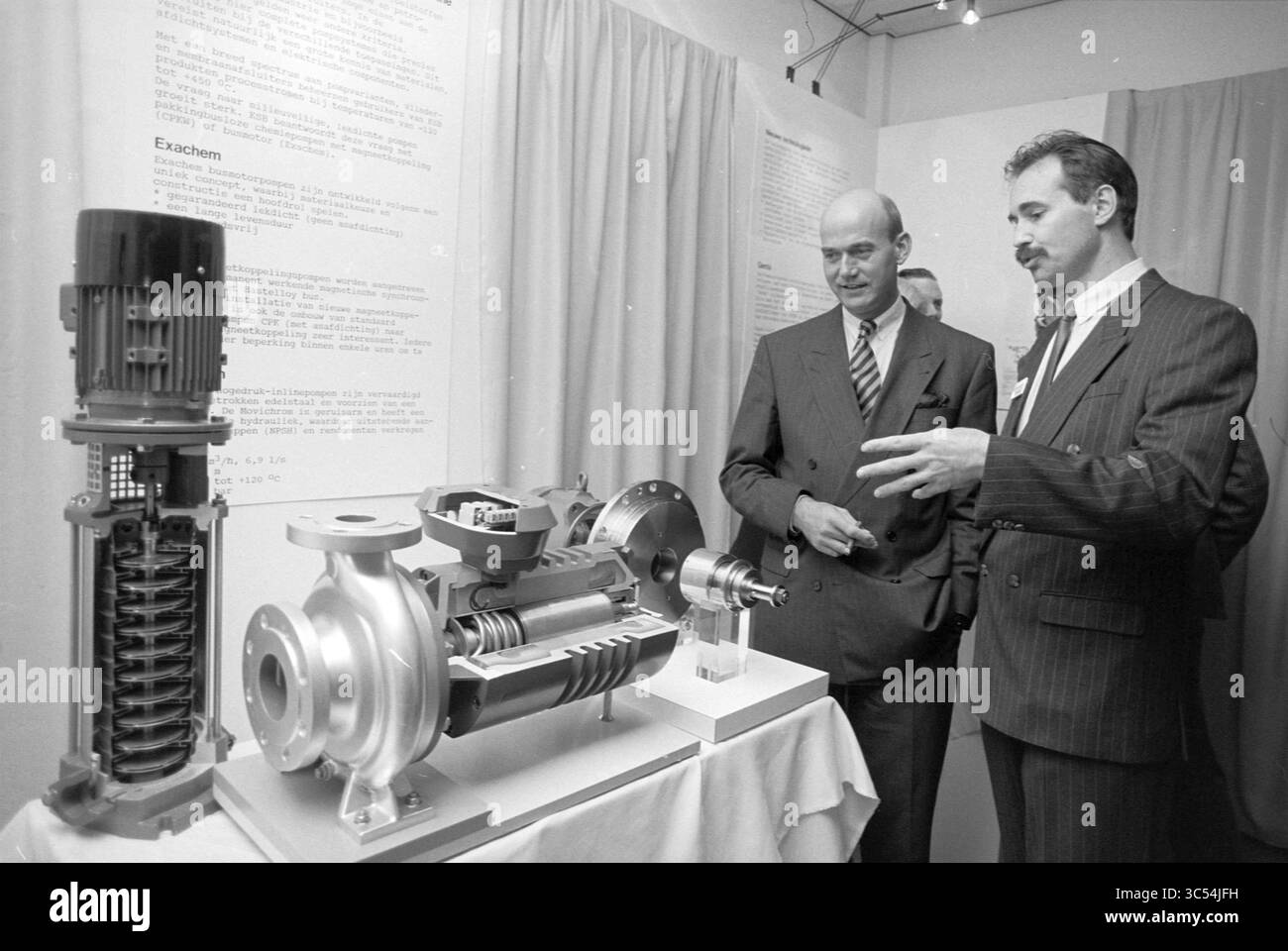 Ouverture d'une usine de pompes, Zwanenburg, 13-04-1994 Whizgle News, Dutch Desk, pays-Bas, 1950-2000 deux hommes s'engagent dans la conversation tout en observant un écran présentant un modèle détaillé d'un système de pompe, mettant en évidence ses composants et les subtilités techniques. La toile de fond comprend un texte informatif, ajoutant du contexte à la technologie présentée. Banque D'Images
