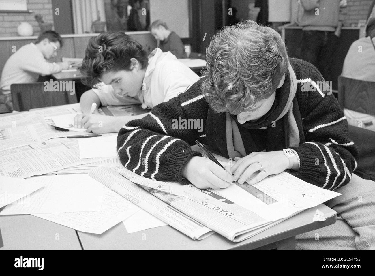 Journée des médias Berlingh College, Beverwijk, Ecoles, Beverwijk, pays-Bas, 22-01-1987 Whizgle News, Dutch Desk, pays-Bas, 1950-2000 étudiants se concentrent intensément sur leur travail, entourés de documents et de documents. L'un est axé sur le dessin avec une règle, tandis qu'un autre semble engagé dans l'écriture, créant une atmosphère de dévouement et d'apprentissage. Banque D'Images