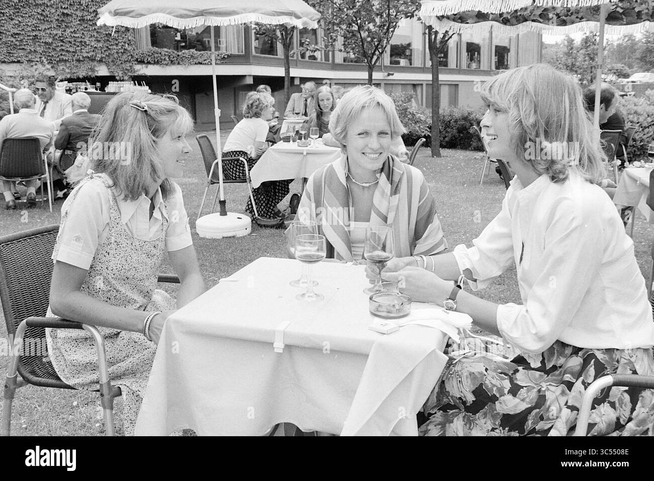 Ouverture jardin d'été Hilton Amsterdam, ouverture, ouvertures, mise en service, photos d'été, 21-06-1978 Whizgle News, Dutch Desk, pays-Bas, 1950-2000 trois femmes s'engagent dans une conversation joyeuse à une table en plein air, dégustant un verre dans un jardin animé entouré d'autres clients. Leurs sourires suggèrent un moment de camaraderie dans une atmosphère détendue. Banque D'Images