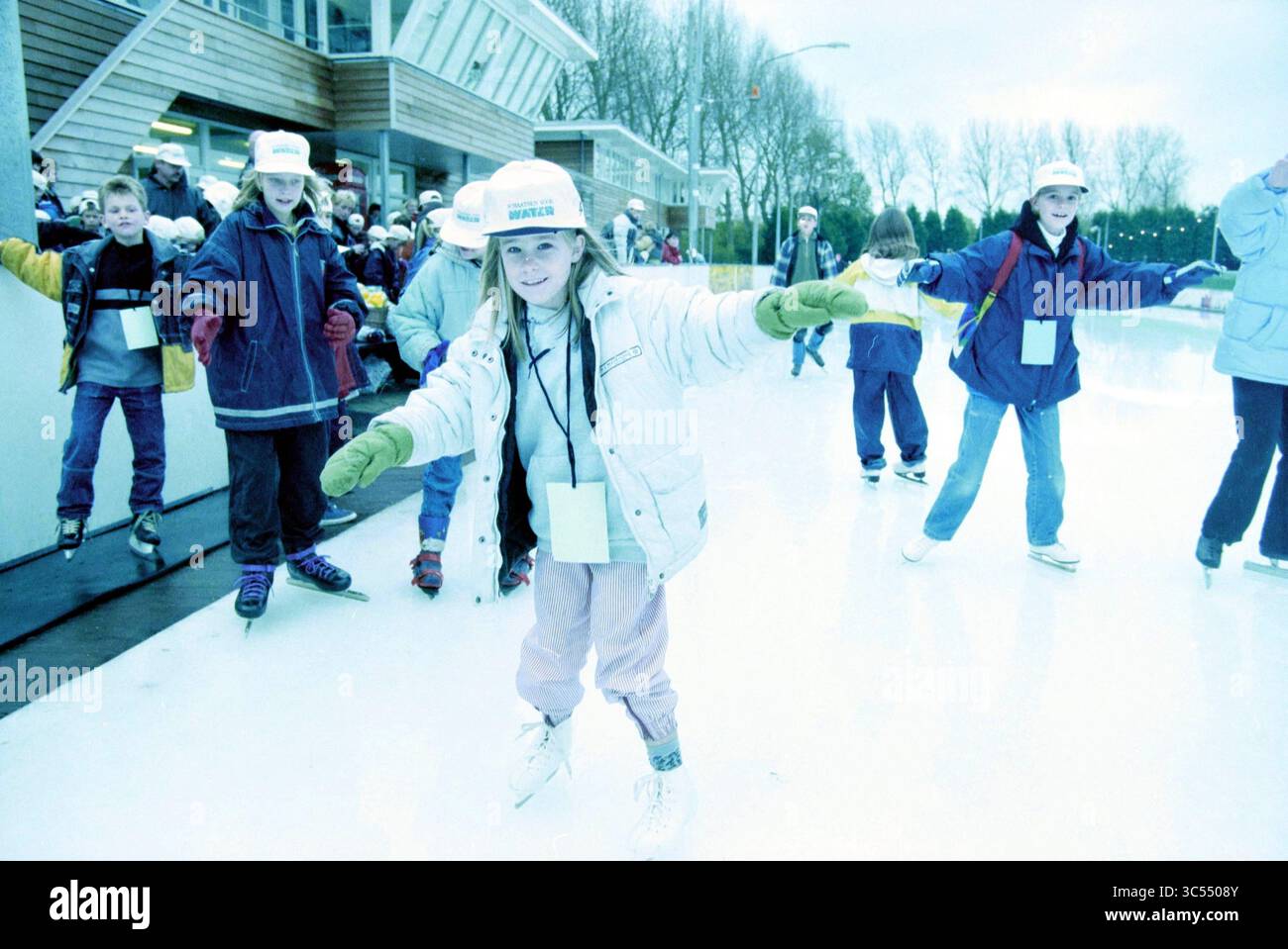 Patinage pour l'eau, Haarlem, pays-Bas, 08-11-1999 Whizgle News, Dutch Desk, pays-Bas, 1950-2000 Un groupe d'enfants profite d'une journée de patinage sur glace, portant des vêtements d'hiver et des chapeaux ludiques. Un enfant glisse gracieusement sur la glace, souriant tandis que les autres patinent en arrière-plan, créant une atmosphère animée et amusante. Banque D'Images