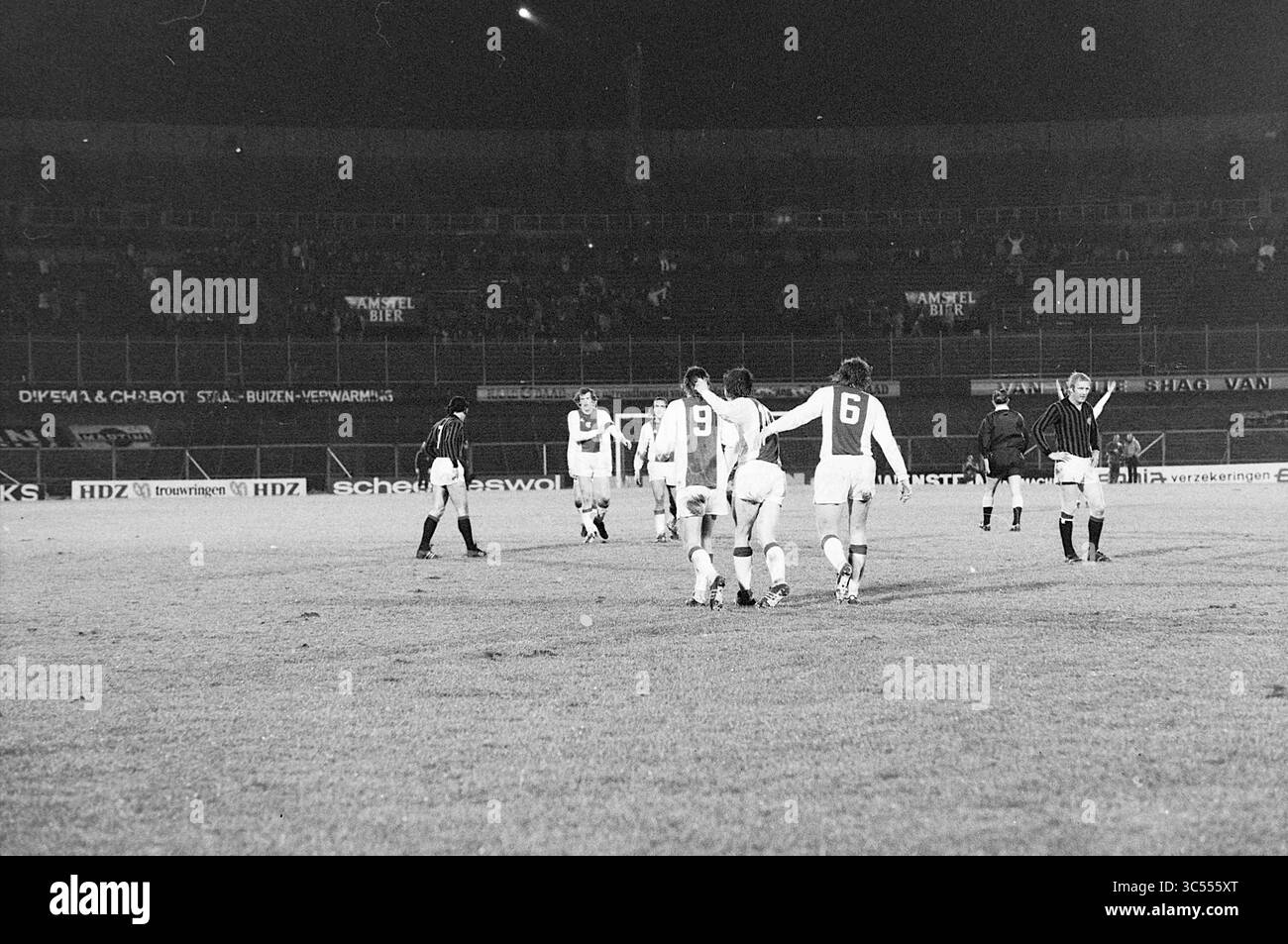 Ajax - A.C. Milan, Football Ajax, 16-01-1974 Whizgle News, Dutch Desk, pays-Bas, 1950-2000 Un groupe de joueurs de football quitte le terrain après un match, faisant preuve de camaraderie et de travail d'équipe. Les stands sont faiblement éclairés, suggérant une atmosphère de jeu nocturne, et un arbitre peut être vu en arrière-plan. Banque D'Images