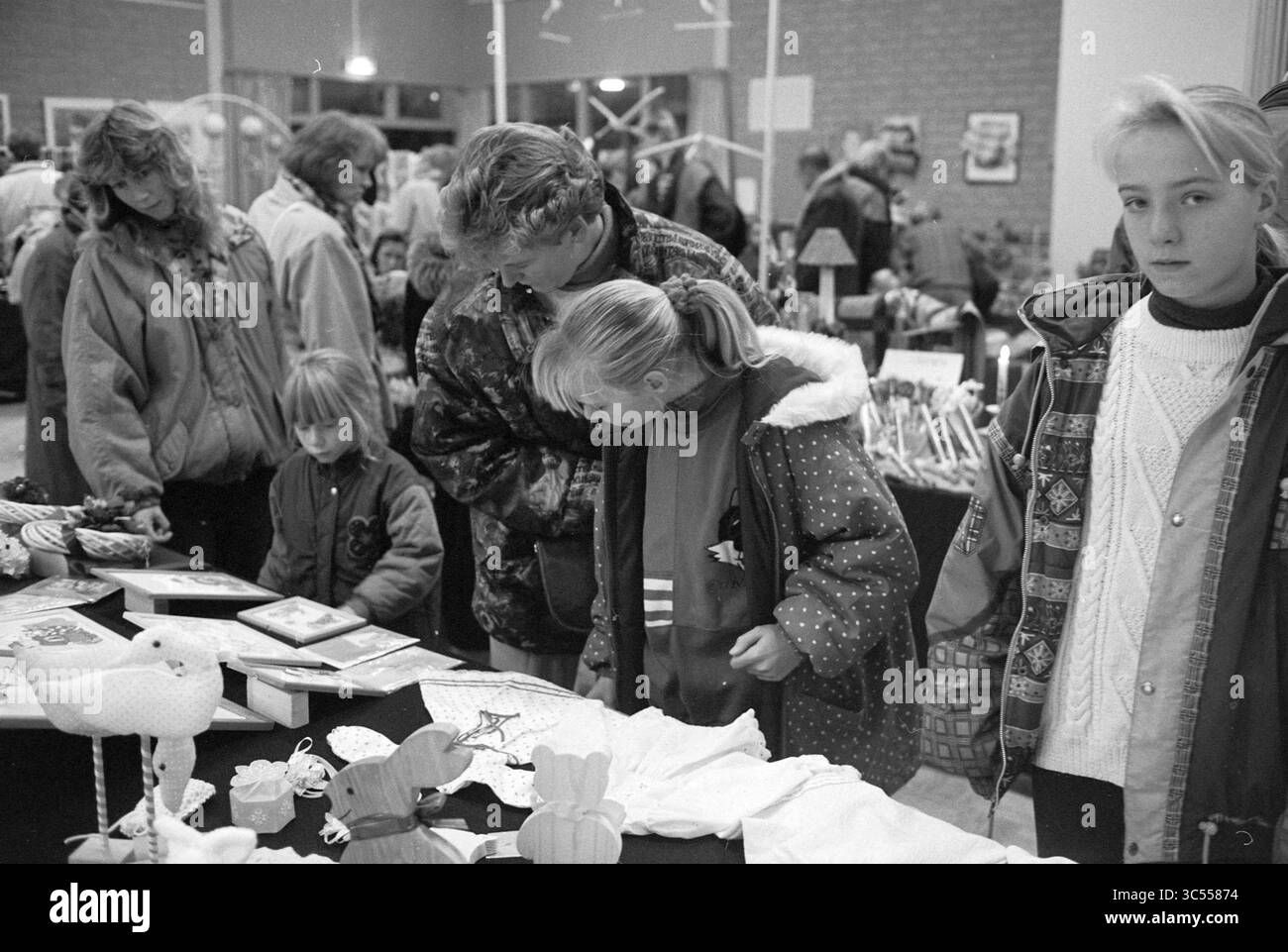 Pakjesmarkt, Velserbroek, 19-11-1993 Whizgle News, Dutch Desk, pays-Bas, 1950-2000 Une scène de marché intérieur animée montre les familles qui parcourent divers objets artisanaux et décorations faits à la main sur des tables, avec des enfants observant et des adultes s'entretenant étroitement avec les affichages. Banque D'Images