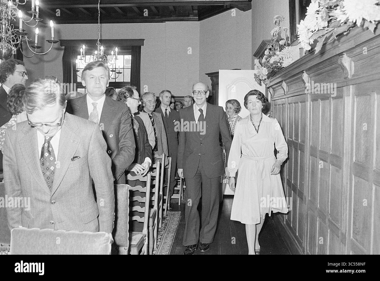 Installation du maire Machielsen Zandvoort, maires, 05-10-1977 Whizgle News, Dutch Desk, pays-Bas, 1950-2000 Un groupe de personnes habillées en tenue formelle marche dans un espace intérieur digne, probablement dans le cadre d'une cérémonie ou d'un rassemblement. L'atmosphère suggère un mélange de célébration et de formalité, avec les participants qui s'engagent dans la conversation et partagent des sourires alors qu'ils se déplacent le long d'un plancher de bois. Banque D'Images