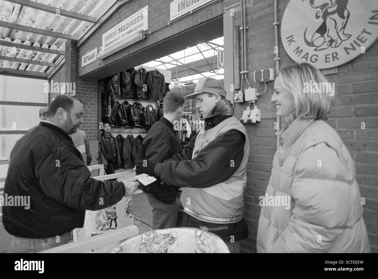 Les travailleurs temporaires commencent au marché noir, Beverwijk, pays-Bas, 16-03-1996 Whizgle News, Dutch Desk, pays-Bas, 1950-2000 Une scène de marché animée montre un vendeur qui remet un achat à un client, tandis qu'un autre client discute avec un vendeur à proximité. En arrière-plan, un affichage de vestes en cuir est visible, ajoutant à l'atmosphère animée. Banque D'Images