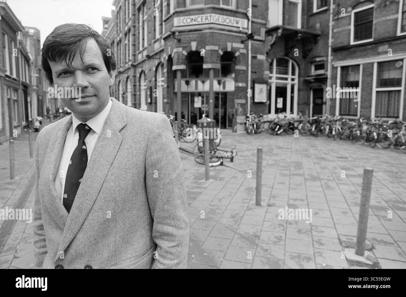 Mark den Hertog, directeur du Concertgebouw, 11-06-1991 Whizgle News, Dutch Desk, pays-Bas, 1950-2000 Un homme en costume sur mesure se tient confiant dans une rue animée, avec le bâtiment emblématique du Concertgebouw en arrière-plan et des vélos alignés le long du trottoir. Banque D'Images