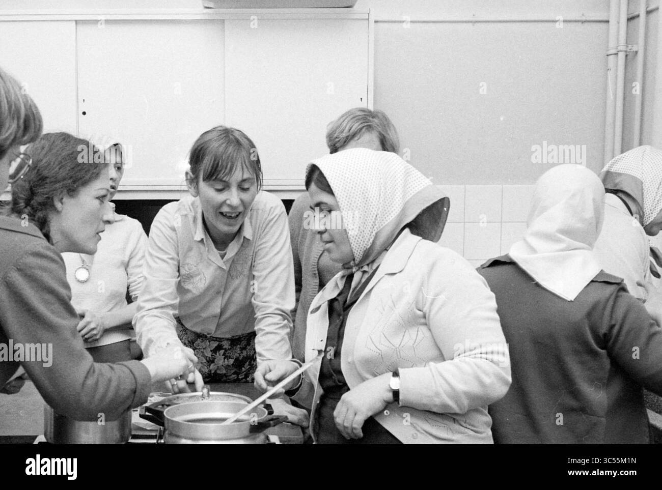 Des femmes turques enseignent la cuisine turque aux femmes néerlandaises, 17-01-1983 Whizgle News, Dutch Desk, pays-Bas, 1950-2000 Un groupe de femmes collaborent avec enthousiasme dans une cuisine, se consacrent à la cuisine et partagent des idées. Leurs expressions ciblées soulignent un sentiment de camaraderie lorsqu'ils travaillent ensemble avec des pots et des ustensiles. Les foulards traditionnels ajoutent une touche culturelle à la scène. Banque D'Images