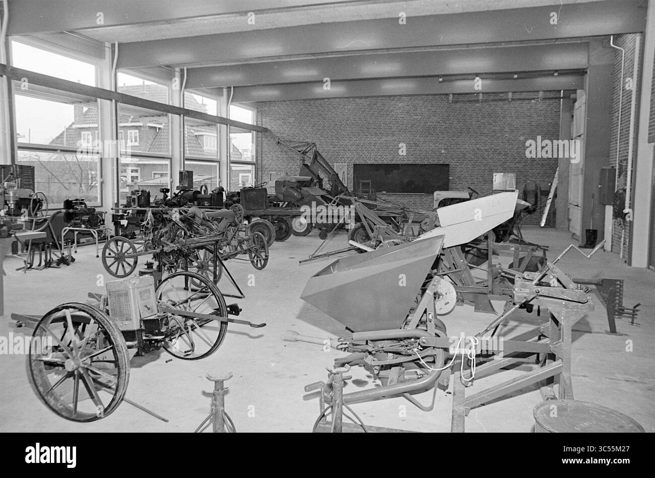 Espace d'exposition de l'école agricole et horticole Hoofddorp Interior, 01-11-1965 Whizgle News, Dutch Desk, pays-Bas, 1950-2000 Un atelier spacieux rempli de diverses machines anciennes et de matériel agricole, y compris des charrues, des chariots et des outils motorisés, tous disposés de manière organisée. L'environnement dispose de grandes fenêtres fournissant de la lumière naturelle, améliorant l'atmosphère industrielle de l'espace. Banque D'Images