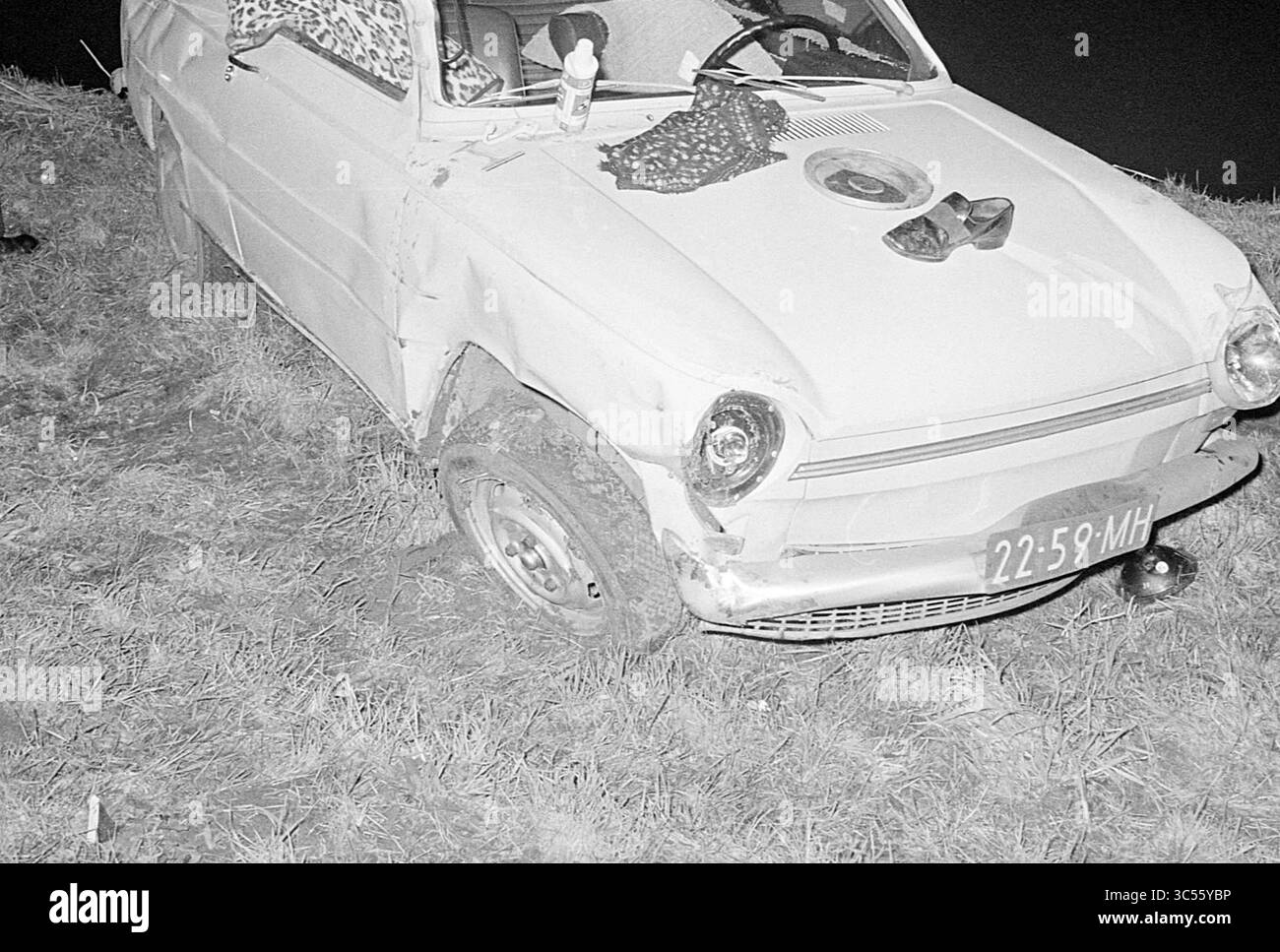 Accident avec voiture, 00-02-1971 Whizgle News, Dutch Desk, pays-Bas, 1950-2000 an abandonné, voiture vintage repose sur l'herbe, montrant des signes d'usure et de dommages. À côté de lui, quelques objets personnels font allusion à un passé oublié, tandis que la forme distinctive du véhicule se démarque de l'environnement naturel. Banque D'Images