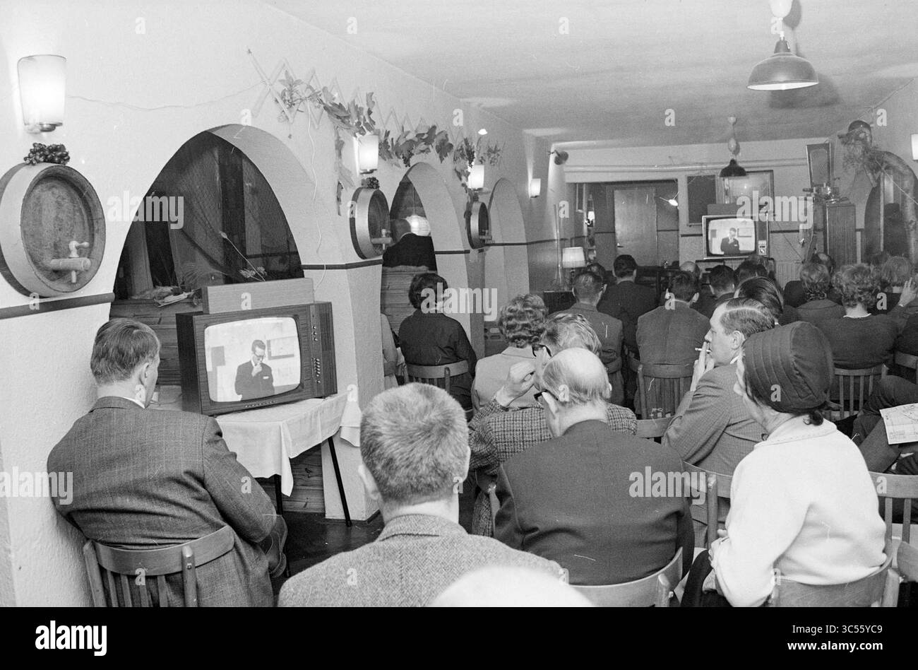 Teach-In Noise pollution Schiphol, Schiphol, 02-11-1967 Whizgle News, Dutch Desk, pays-Bas, 1950-2000 Un groupe de personnes est assis tranquillement dans une pièce confortable, engagé avec une télévision diffusant un segment d'information. Ils regardent attentivement, certains individus prenant des notes, tandis que l'ambiance est rehaussée par un décor vintage et un éclairage chaleureux. Banque D'Images