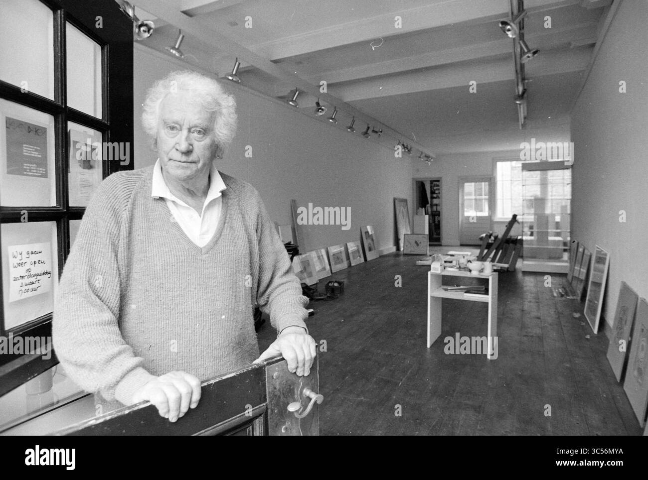Jules CH@@ in Lieven de Key Gallery, Haarlem, Nassaulaan, pays-Bas, 25-02-1991 Whizgle News, Dutch Desk, pays-Bas, 1950-2000 un homme âgé aux cheveux blancs se tient à l'entrée d'une galerie d'art spacieuse, entouré d'œuvres encadrées appuyées contre les murs. La galerie dispose de parquet et d'une grande lumière naturelle qui traverse une grande fenêtre, créant une atmosphère sereine parfaite pour l'affichage Banque D'Images