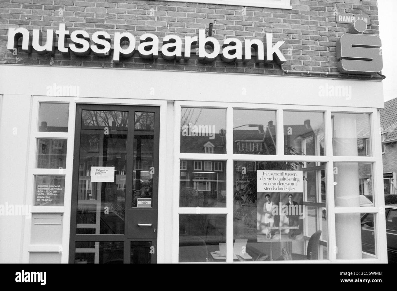 Visa publicité au bureau Nutsspaarbank, Nuts, United Savings Banks, 25-03-1988 Whizgle News, Dutch Desk, les pays-Bas, 1950-2000 Une devanture arborant le nom « nutssparabank » bien en vue au-dessus d'une grande fenêtre, offrant une vue sur l'intérieur. Un panneau dans la fenêtre fournit des informations, tandis que la zone environnante comprend des reflets des bâtiments et des arbres à proximité. Banque D'Images