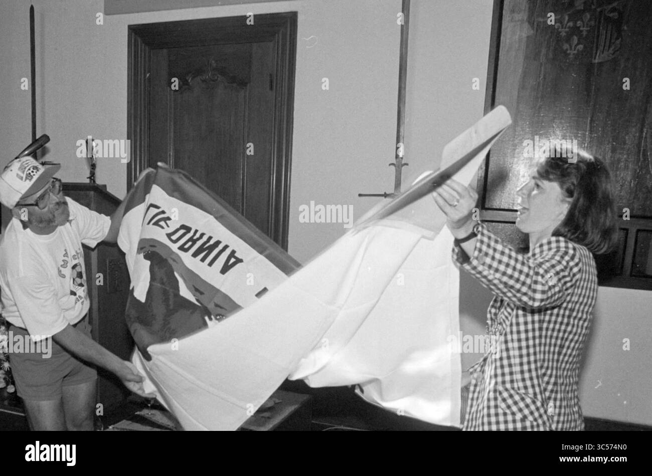 Montrer le drapeau de la République de Californie, 02-08-1994 Whizgle News, Dutch Desk, pays-Bas, 1950-2000 Un homme et une femme sont engagés dans un échange animé, tirant tous deux sur un grand drapeau qui est entre leurs mains. Le cadre semble être à l'intérieur, avec des panneaux de bois et des éléments décoratifs en arrière-plan, ajoutant un sentiment d'occasion à leur interaction. Banque D'Images