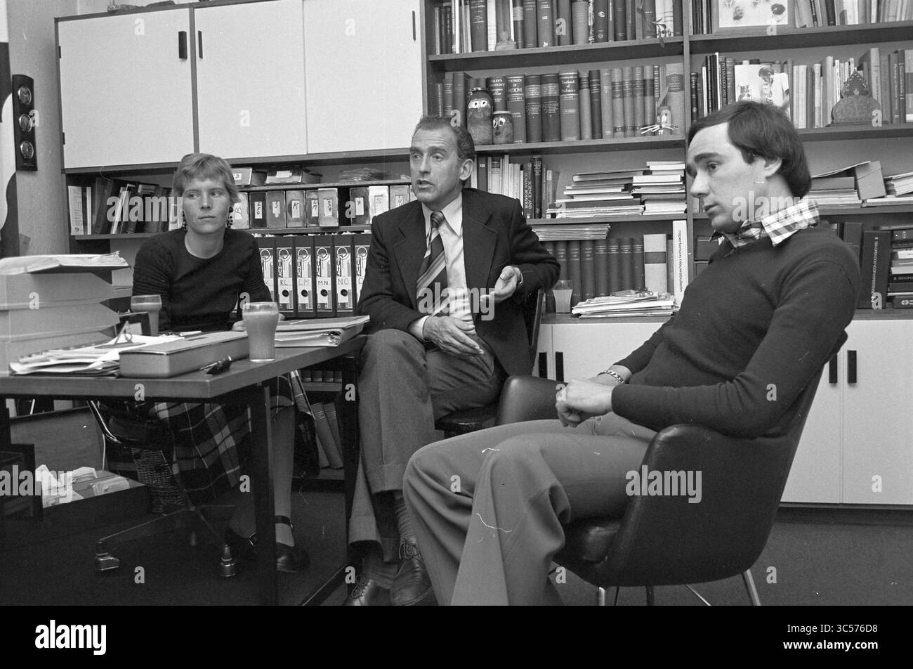 M. Weidema et ses collègues, c. Edenstraat, H'lem (médecins du sport), médecins, Haarlem, Van Eedenstraat, pays-Bas, 19-05-1975 Whizgle News, Dutch Desk, pays-Bas, 1950-2000 Un groupe de trois personnes entreprend une discussion sérieuse dans un bureau, entouré d'étagères remplies de divers volumes et documents. Une personne est assise à une table, regardant attentivement une autre, qui semble faire un point, tandis que la troisième personne écoute attentivement. L'atmosphère suggère un échange d'idées collaboratif. Banque D'Images