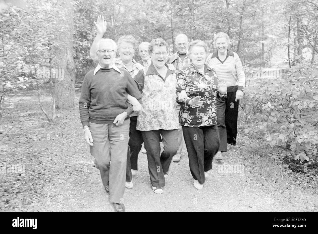MRS out, maison de vacances Heideheuvel, Beekbergen, vacances, vacanciers, 21-09-1978 Whizgle News, Dutch Desk, pays-Bas, 1950-2000 Un groupe joyeux de personnes âgées marchant ensemble sur un chemin, souriant et bavardant, avec des arbres et de la verdure qui les entourent. Certains agitent, incarnant un sentiment de camaraderie et de bonheur. Banque D'Images
