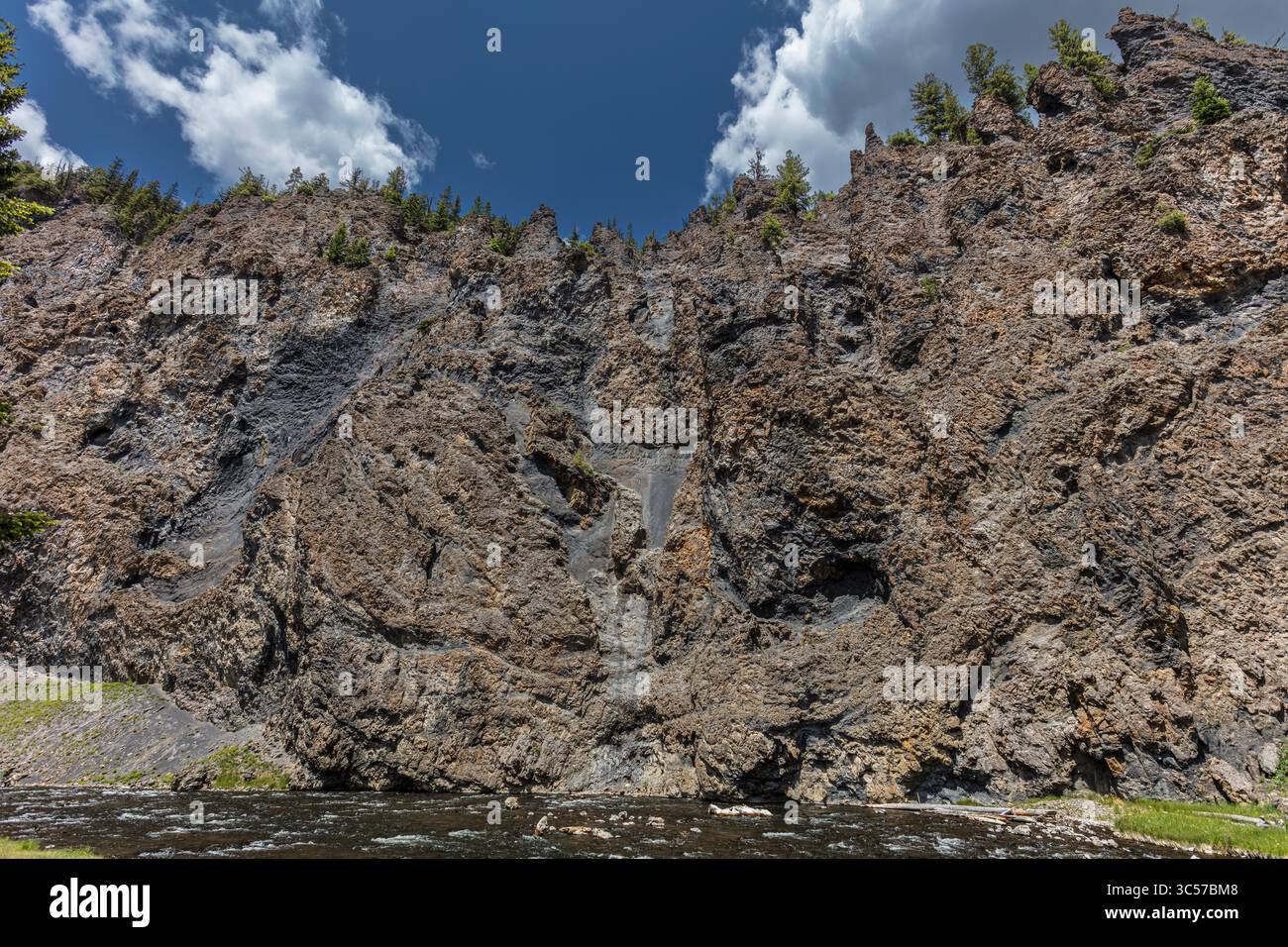 Les falaises qui s'élèvent au-dessus de la rivière Firehole dans le parc national de Yellowstone sont composées de roches volcaniques sombres, principalement de rhyolite et de basalte Banque D'Images