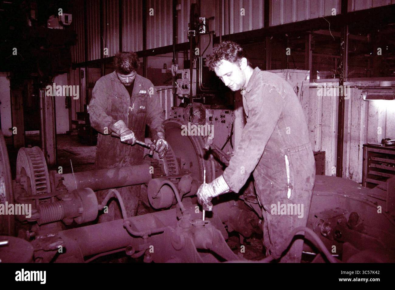 NS atelier divers départements, 18-03-1999 Whizgle News, Dutch Desk, pays-Bas, 1950-2000 deux travailleurs réparent diligemment des machines dans un atelier, concentrés sur leurs tâches. L'un utilise une clé sur un gros composant, tandis que l'autre inspecte une pièce, portant à la fois une combinaison et des gants, entourée d'équipements industriels et d'outils. Banque D'Images