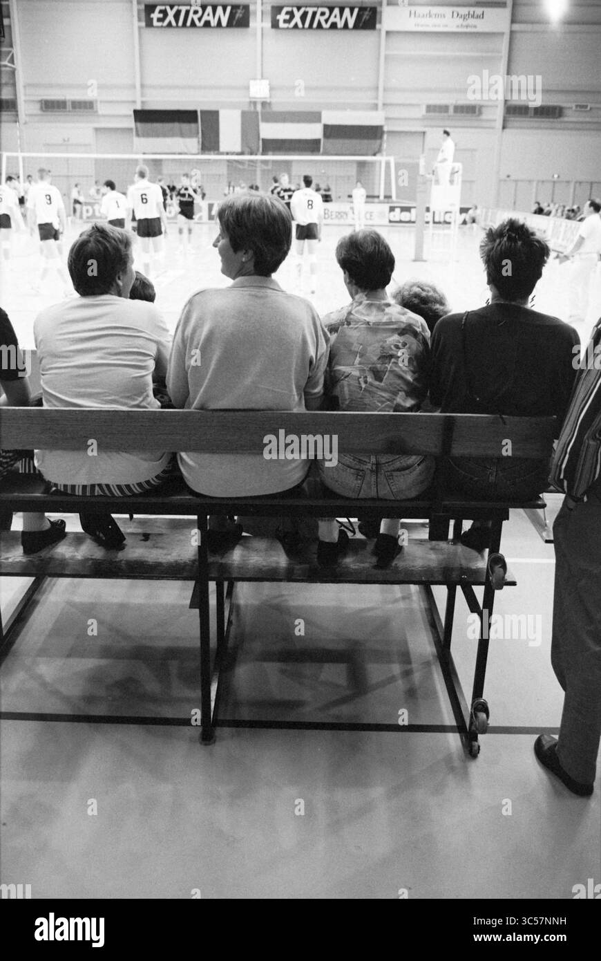 1 an Extran hall, Haarlem, pays-Bas, 31-08-1994 Whizgle News, Dutch Desk, pays-Bas, 1950-2000 Un groupe d'individus est assis sur un banc, regardant un match de volley-ball en arrière-plan. Leur posture détendue et leur concentration indiquent le plaisir, tandis que les joueurs sont vus activement engagés dans le jeu au-delà d'eux. Banque D'Images