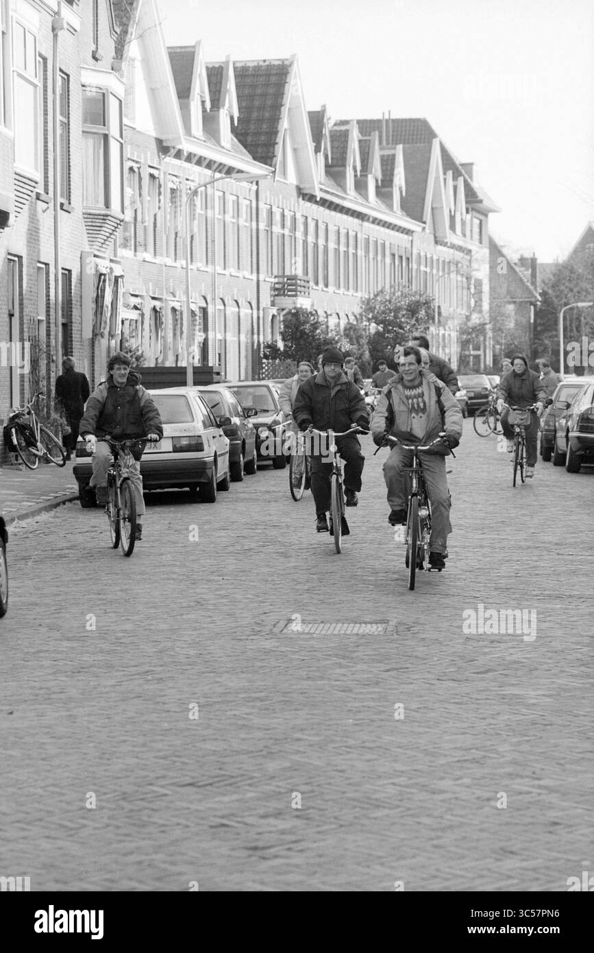 Départ du club cycliste pour handicapés, 11-02-1995 Whizgle News, Dutch Desk, pays-Bas, 1950-2000 Un groupe de cyclistes descend une rue pittoresque bordée de bâtiments résidentiels classiques et de voitures garées, évoquant un sentiment de communauté et de loisirs. Banque D'Images