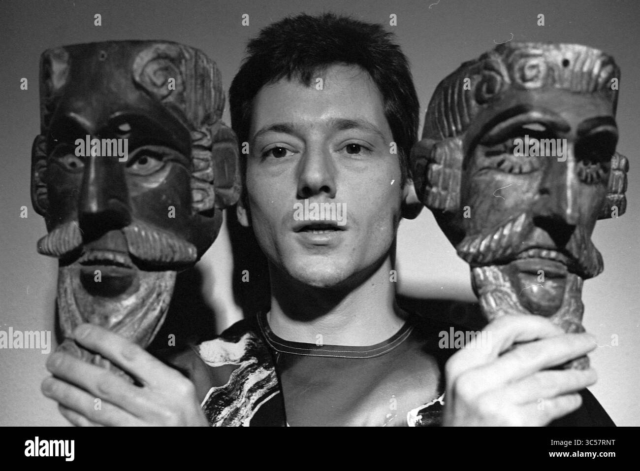 Boutique Oriental store, 09-08-1993 Whizgle News, Dutch Desk, pays-Bas, 1950-2000 Une personne se tient entre deux grands masques finement sculptés, chacun représentant une figure à face arrière avec des traits faciaux distincts et des coiffures élaborées. L'individu semble contemplatif, regardant la caméra tout en tenant les masques bien en évidence de chaque côté. Banque D'Images