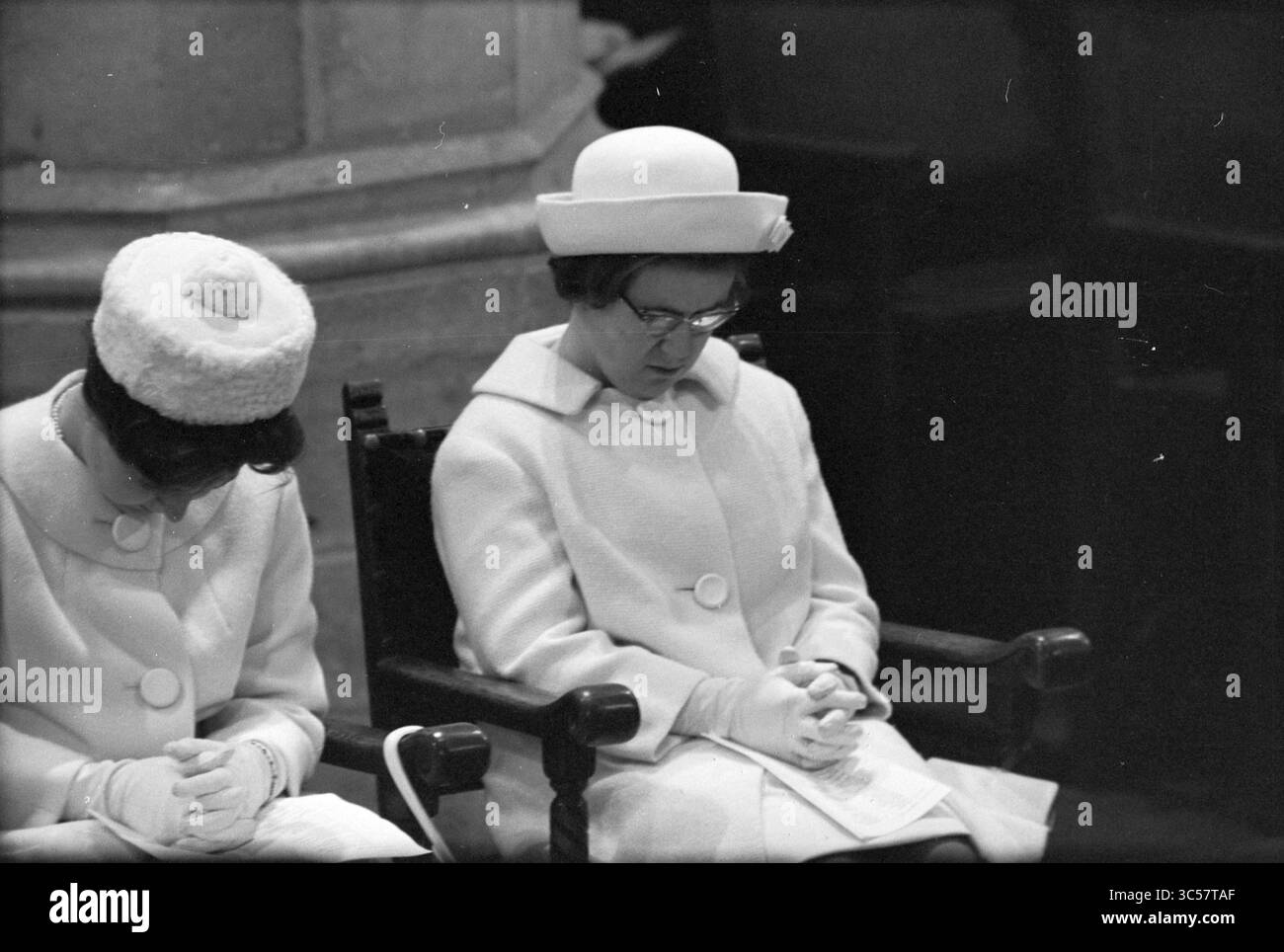 Funérailles de la reine Wilhelmina et inhumation dans le Nieuwe Kerk à Delft, Delft, 08-12-1962 Whizgle News, Dutch Desk, pays-Bas, 1950-2000 deux femmes, vêtues d'élégants manteaux et chapeaux, s'assoient côte à côte, la tête inclinée et les mains serrées dans la prière ou la contemplation, entourées d'une atmosphère de solennité et de révérence. Banque D'Images