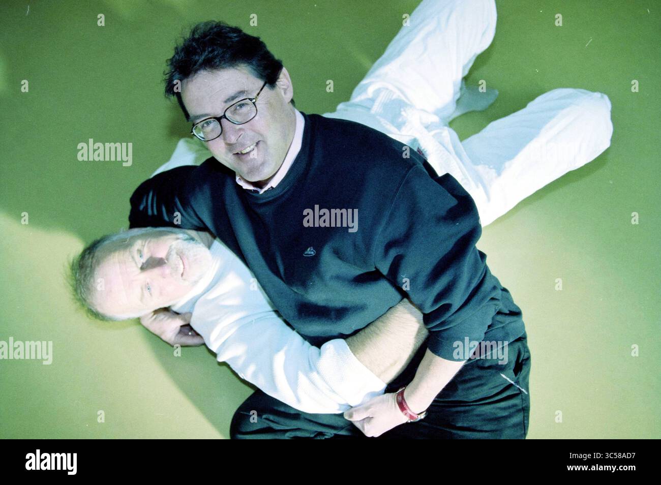 Directeur Cr. vd Geest, 27-10-2004 Whizgle News, Dutch Desk, pays-Bas, 1950-2000 deux hommes sont engagés dans une manœuvre de grappin, l'un positionné au sol et l'autre penché sur lui, semblant l'aider ou l'enseigner. Ils portent tous les deux des vêtements de couleur claire, et le cadre suggère une atmosphère détendue, peut-être un contexte d'arts martiaux ou d'entraînement. Les expressions sur leurs visages indiquent la camaraderie et la concentration lorsqu'ils interagissent. Banque D'Images