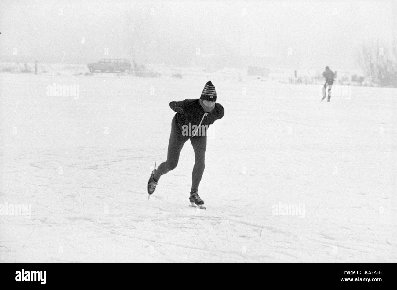 Skating photos Leidsevaart, Skating, Haarlem, Leidsevaart, pays-Bas, 23-12-1981 Whizgle News, Dutch Desk, pays-Bas, 1950-2000 Un patineur glisse sans effort sur une surface gelée, mettant en valeur son habileté et sa vitesse dans un paysage hivernal, tandis qu'un autre patine au loin. La scène transmet un sentiment de tranquillité et d'activité de plein air dans des conditions froides. Banque D'Images