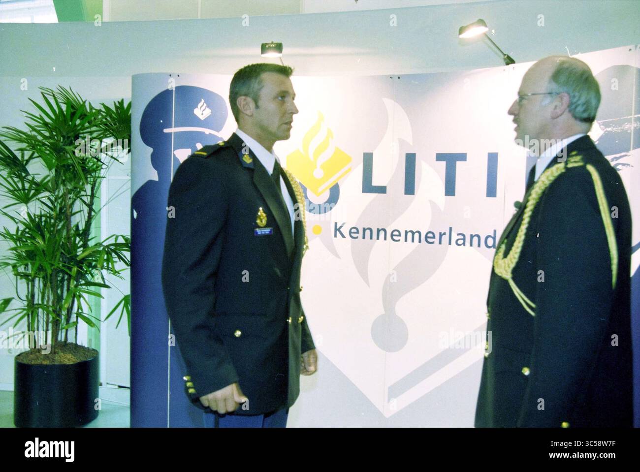 Officiers assermentés, Haarlem, pays-Bas, 26-02-2001 Whizgle News, Dutch Desk, pays-Bas, 1950-2000 deux individus en uniforme s'engagent dans une conversation près d'une toile de fond avec le mot « POLITIE » et le nom « Kennemerland ». Une plante est visible en arrière-plan, ajoutant une touche de verdure à la scène. Banque D'Images