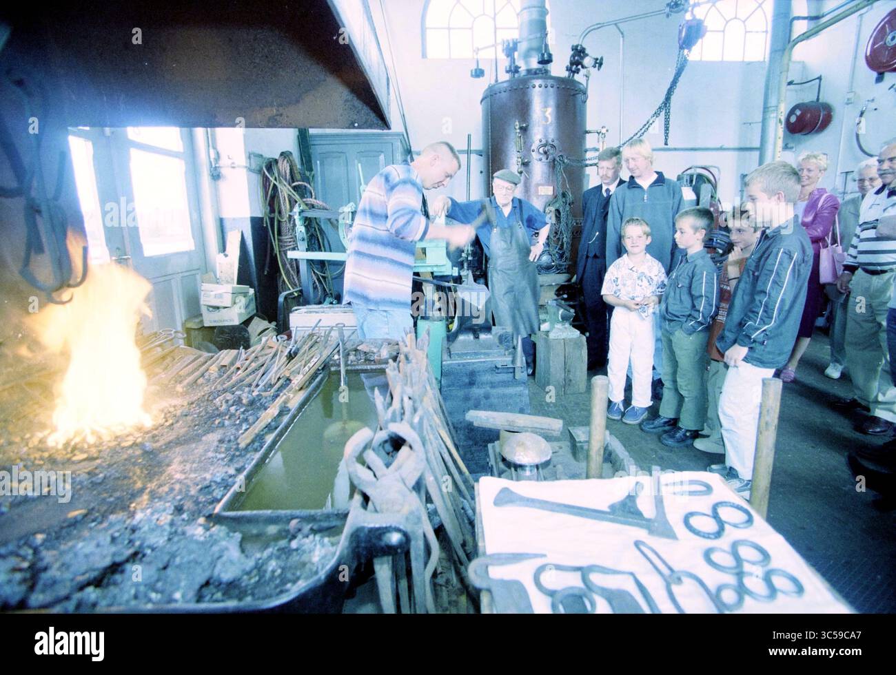 Journée repas à la station de pompage Halfweg, Halfweg, Haarlemmerstraatweg, 16-06-2001 Whizgle News, Dutch Desk, pays-Bas, 1950-2000 Un groupe de spectateurs regarde attentivement comme un forgeron démontre l'art du travail des métaux, avec des charbons brillants et divers outils entourant la forge, soulignant le savoir-faire traditionnel impliqué dans le commerce. Banque D'Images