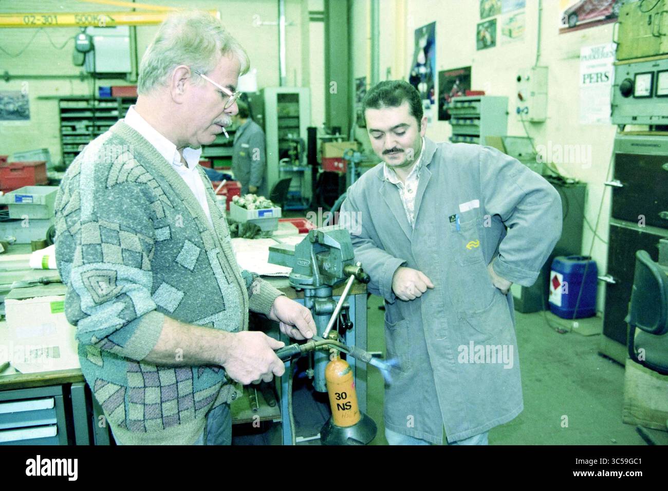 Ouverture du département technique principal de l'atelier NS, Haarlem, pays-Bas, 25-11-1999 Whizgle News, Dutch Desk, pays-Bas, 1950-2000 deux hommes participent à une démonstration pratique d'un outil ou d'une machine dans un atelier. Un homme fait la démonstration d'une technique tandis que l'autre observe avec intérêt. Divers outils et équipements sont visibles en arrière-plan, mettant l'accent sur l'environnement industriel. Banque D'Images