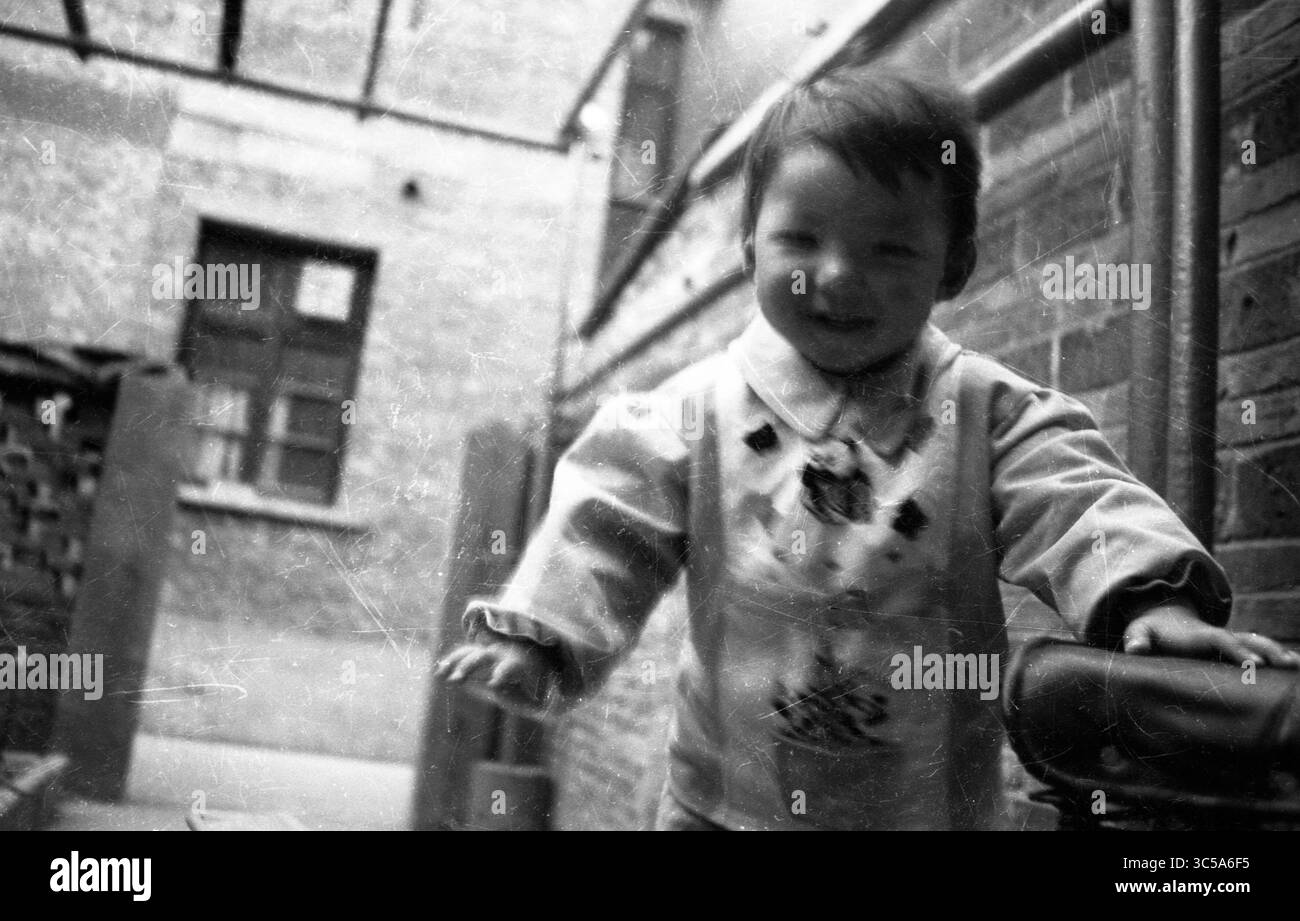 Vintage noir et blanc film rayé Portrait d'enfant souriant dans la cour de briques Banque D'Images