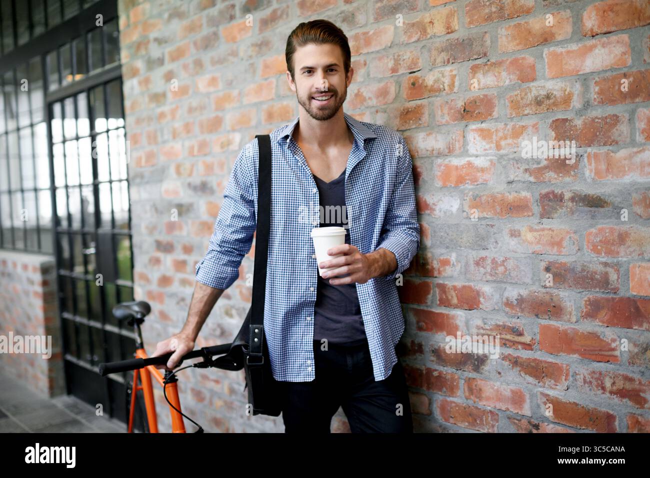 Vélo, portrait et sourire de l'homme d'affaires sur le mur de briques avec café pour le début du travail ou le matin. Carbone neutre, écologique ou net zéro et heureux Banque D'Images