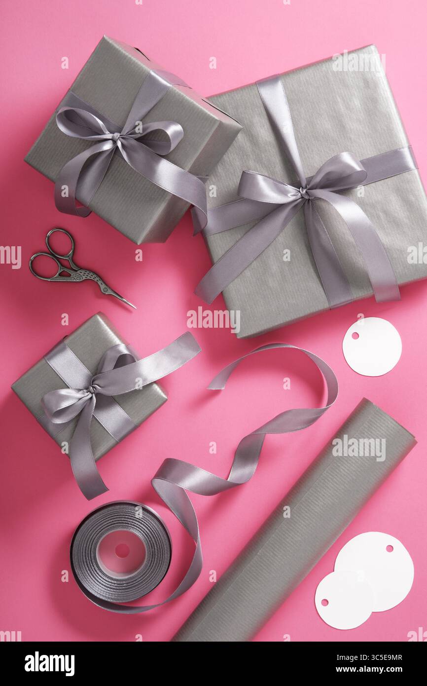 Emballage cadeau. Papier gris, ruban argenté, ciseaux sur fond rose. Vertical, placer pour le texte Banque D'Images