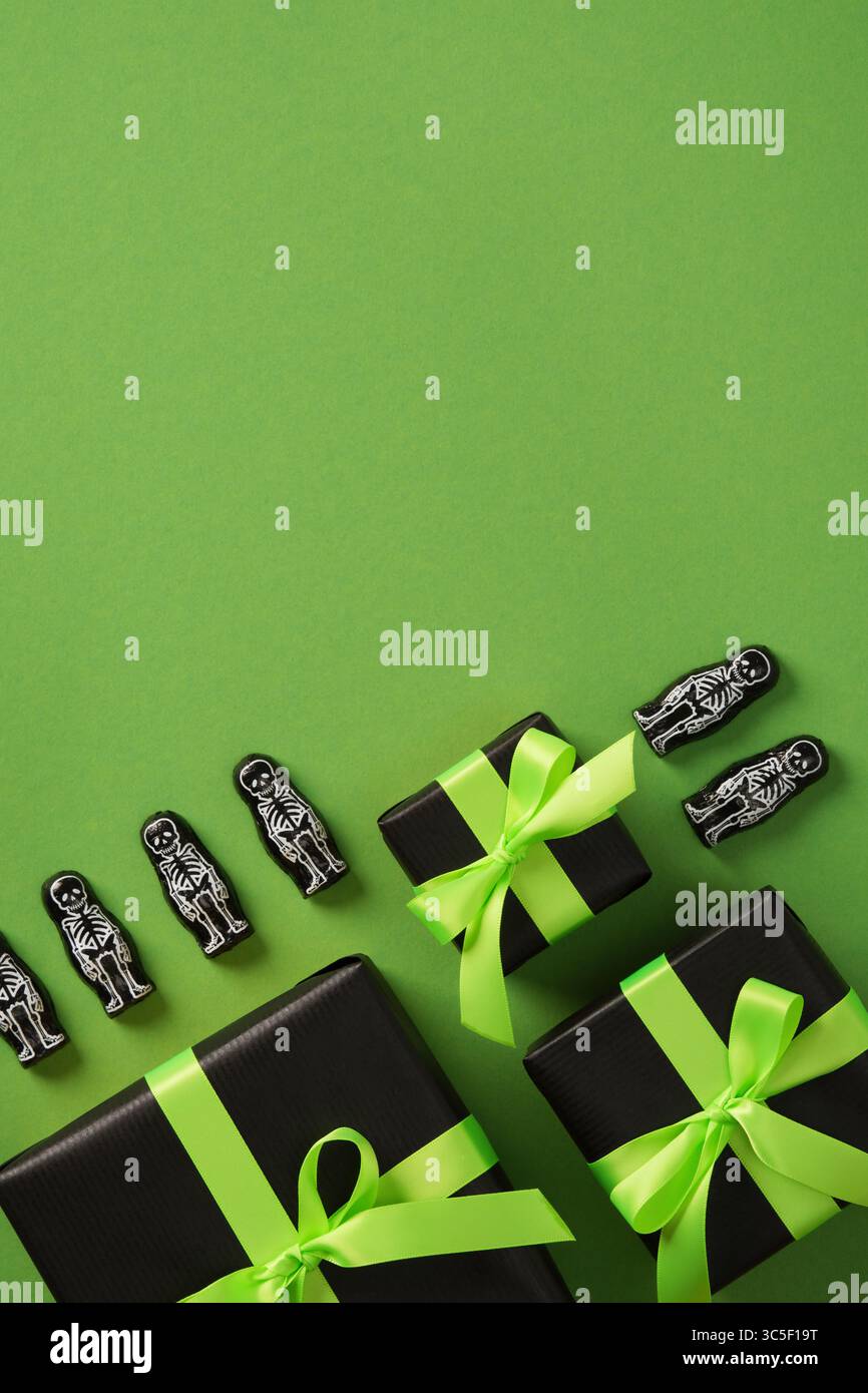 Boîtes-cadeaux Halloween avec des rubans verts et des décorations squelette sur fond vert. Place pour votre texte. Banque D'Images