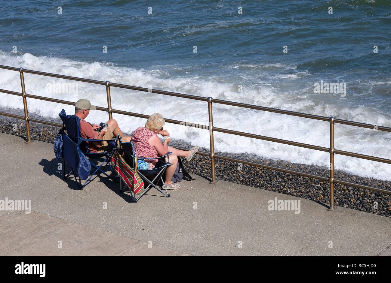 couple senior assis sur la promenade de sheringham, nord de norfolk, angleterre Banque D'Images
