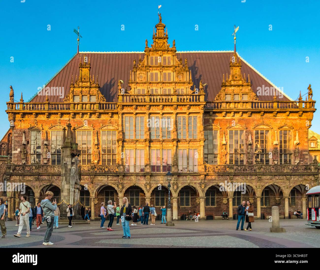 Un couple prend une photo avec un téléphone portable devant l'emblématique façade sud-ouest du célèbre hôtel de ville gothique sur la place du marché de Brême... Banque D'Images