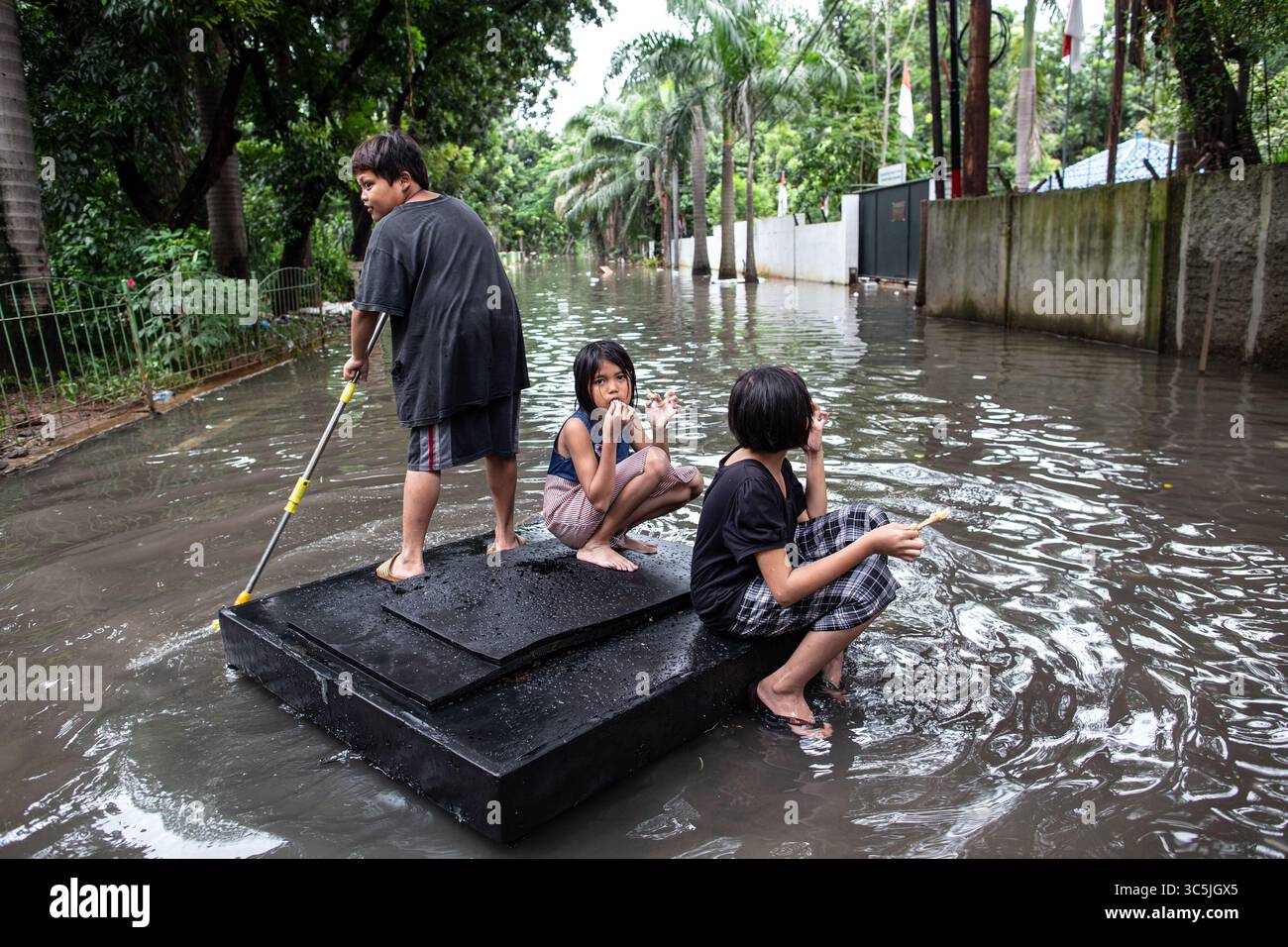25 février 2020, Jakarta, Jakarta, Indonésie : des enfants flottent sur un radeau de fortune dans une rue remplie d'eau alors que des inondations généralisées frappent la capitale indonésienne, Jakarta. De nombreuses maisons, rues, routes et voies ferrées sont inondées. (Crédit image : © Donal Husni/ZUMA Wire) Banque D'Images