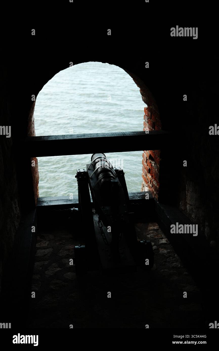 Canon historique à l'intérieur de la forteresse Golubac pointant vers le Danube, vu à travers une fenêtre voûtée en briques. Vue dégagée avec éclairage spectaculaire Banque D'Images